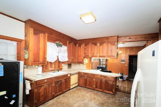 kitchen featuring kitchen peninsula, white appliances, wood walls, and sink