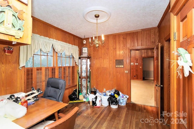 office area with a notable chandelier, wood walls, crown molding, and dark wood-type flooring