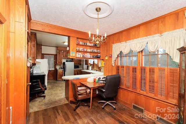 home office featuring a textured ceiling, wood walls, dark hardwood / wood-style floors, and an inviting chandelier