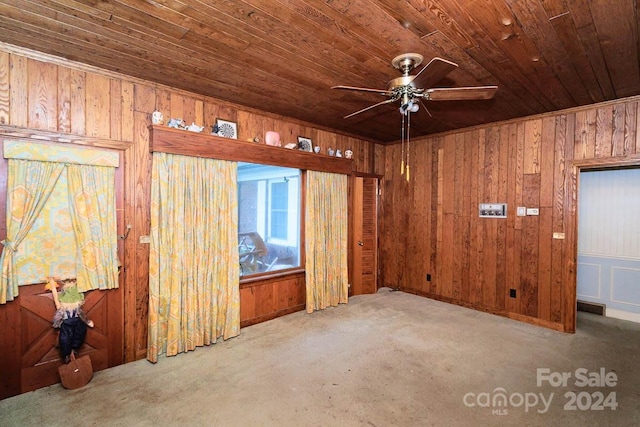 carpeted empty room featuring ceiling fan, wood ceiling, and wood walls