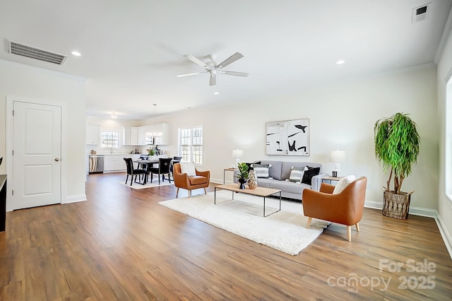 living room with hardwood / wood-style floors, ceiling fan, and ornamental molding