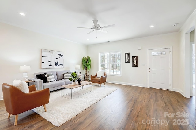 living room with crown molding, ceiling fan, and dark wood-type flooring