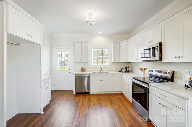 kitchen featuring white cabinetry, sink, stainless steel appliances, dark hardwood / wood-style flooring, and ornamental molding