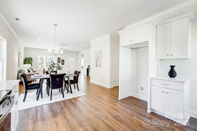 dining space with ceiling fan, crown molding, and light hardwood / wood-style flooring