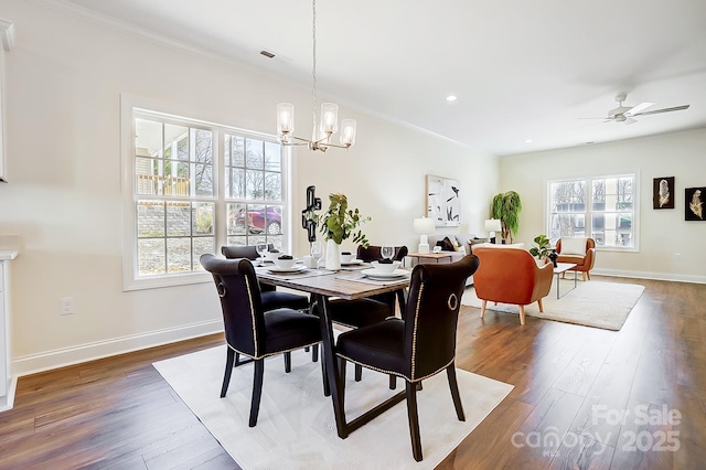 dining room featuring dark wood-type flooring, ceiling fan with notable chandelier, and ornamental molding