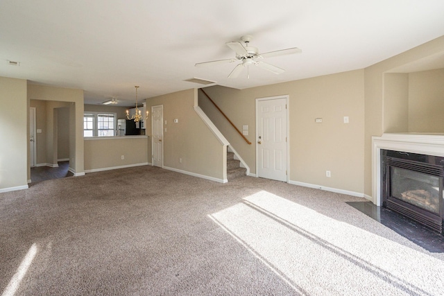 unfurnished living room featuring carpet and ceiling fan with notable chandelier