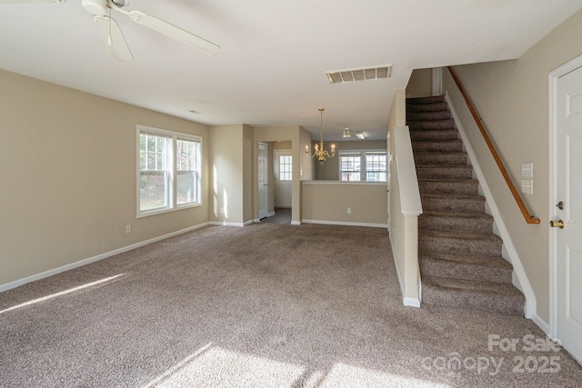 unfurnished living room featuring carpet floors, a healthy amount of sunlight, and ceiling fan with notable chandelier