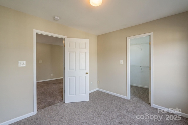 unfurnished bedroom featuring a spacious closet, a closet, and light colored carpet