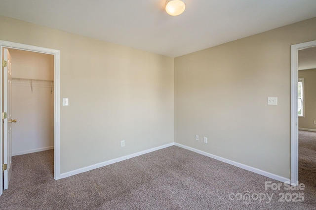 unfurnished bedroom with carpet flooring, a walk in closet, and a closet