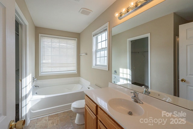 bathroom with vanity, toilet, and a tub