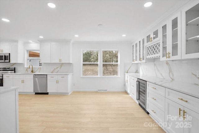 kitchen featuring wine cooler, appliances with stainless steel finishes, backsplash, and white cabinets