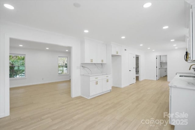 kitchen featuring white cabinetry, light stone counters, sink, and light hardwood / wood-style flooring