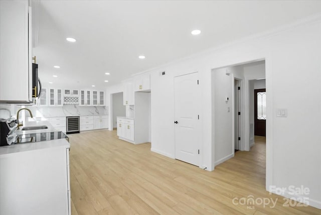 kitchen featuring sink, white cabinetry, tasteful backsplash, light hardwood / wood-style floors, and beverage cooler