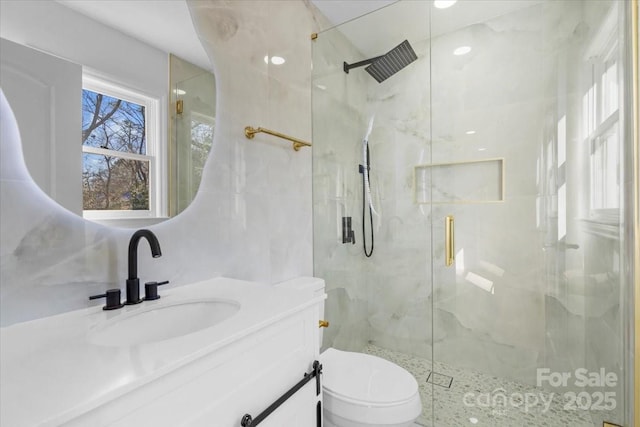 bathroom featuring a shower with door, vanity, and toilet