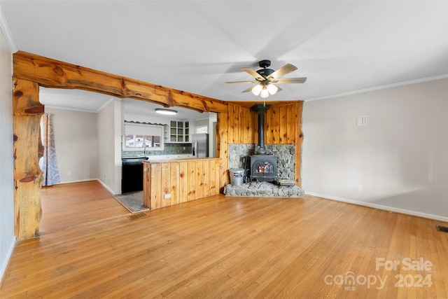 kitchen with a wood stove, stainless steel refrigerator with ice dispenser, decorative backsplash, black dishwasher, and light hardwood / wood-style floors