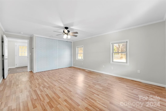 empty room featuring light hardwood / wood-style floors, a wealth of natural light, and crown molding