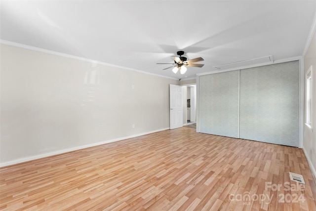 unfurnished bedroom with ceiling fan, a closet, ornamental molding, and light hardwood / wood-style flooring