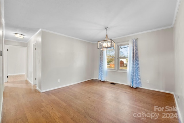 spare room featuring a chandelier, light hardwood / wood-style flooring, and crown molding