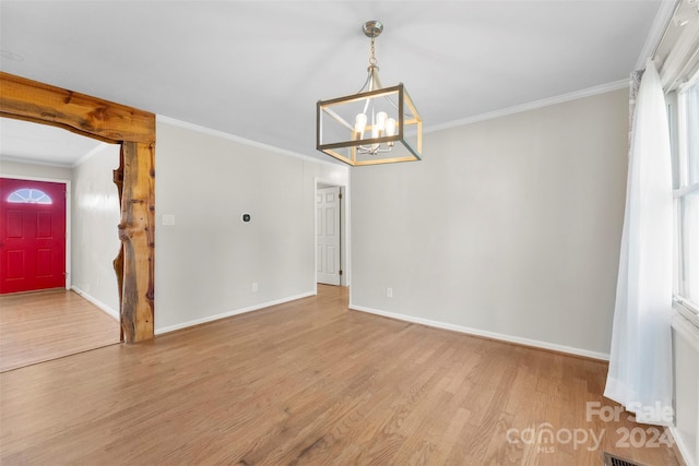 unfurnished dining area featuring crown molding, light hardwood / wood-style flooring, and an inviting chandelier