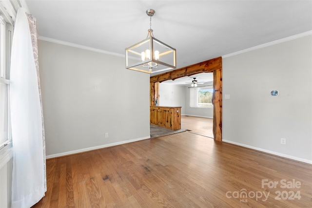 unfurnished dining area featuring hardwood / wood-style floors, ceiling fan with notable chandelier, and crown molding