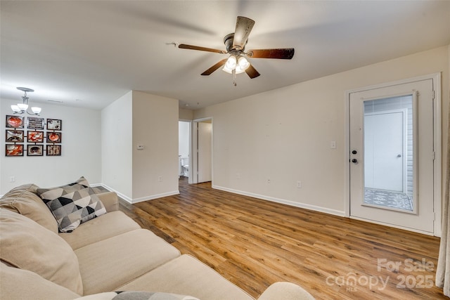 living room featuring wood-type flooring and ceiling fan with notable chandelier