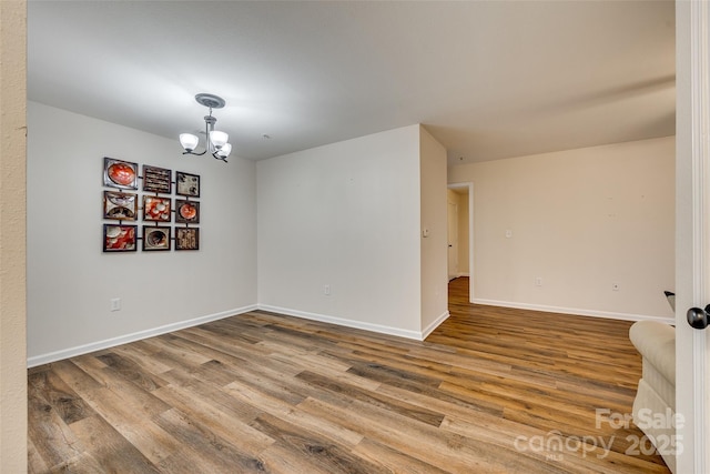 spare room with hardwood / wood-style floors and an inviting chandelier