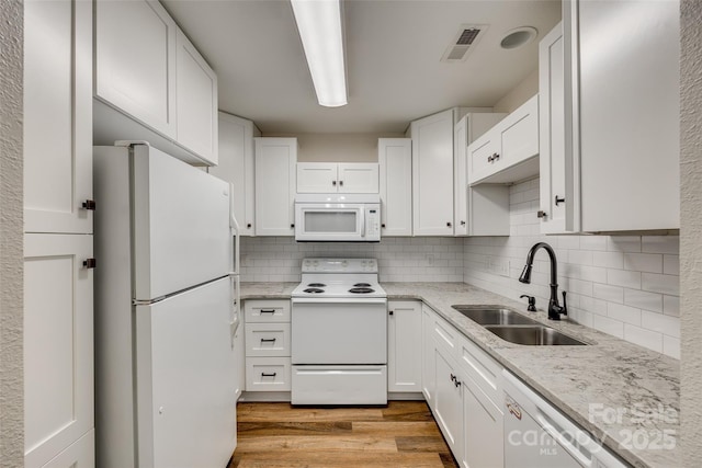 kitchen featuring light wood-type flooring, tasteful backsplash, white appliances, sink, and white cabinetry