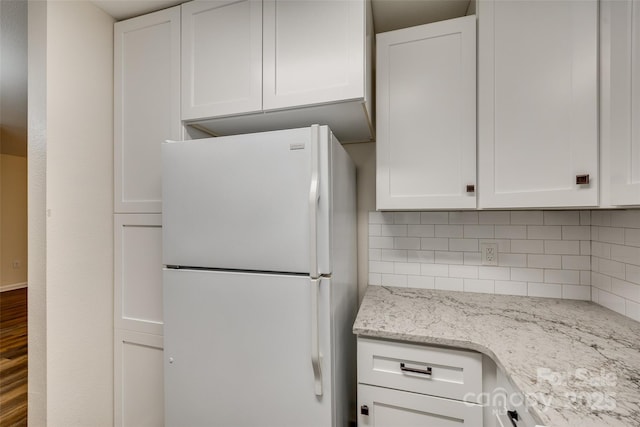 kitchen featuring backsplash, light stone countertops, white cabinets, and white refrigerator