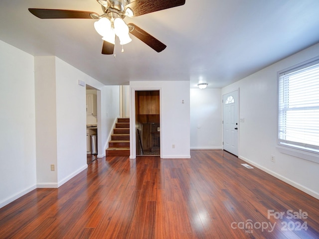 unfurnished living room featuring ceiling fan and dark wood-type flooring