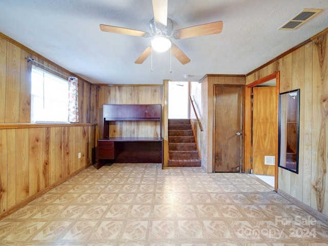 unfurnished bedroom featuring ceiling fan, wooden walls, and crown molding