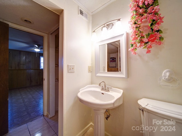 bathroom featuring tile patterned floors, a textured ceiling, ceiling fan, crown molding, and toilet