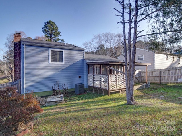 rear view of house featuring a wooden deck, a yard, and central AC