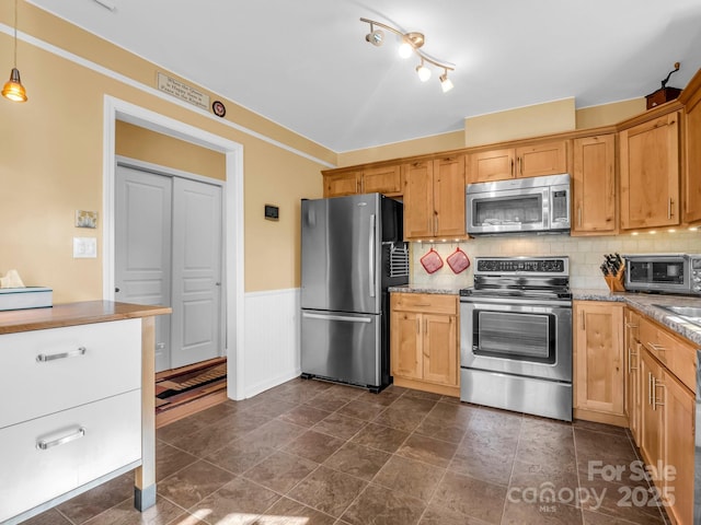 kitchen featuring decorative light fixtures, light stone countertops, appliances with stainless steel finishes, and tasteful backsplash