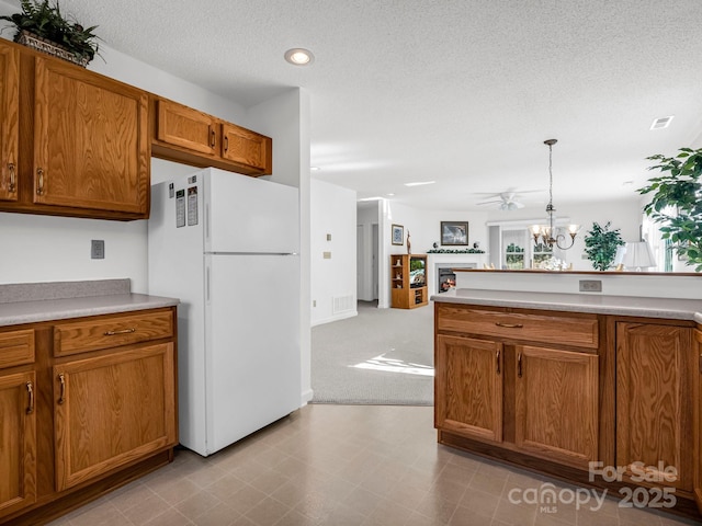 kitchen with white fridge, hanging light fixtures, a textured ceiling, and an inviting chandelier