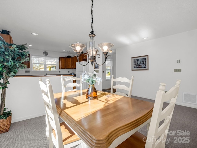 dining area with light colored carpet, a wealth of natural light, and an inviting chandelier