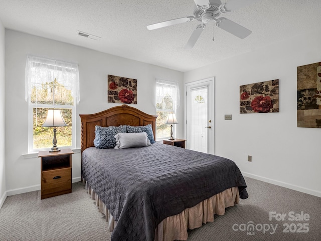 bedroom featuring multiple windows, ceiling fan, light colored carpet, and a textured ceiling