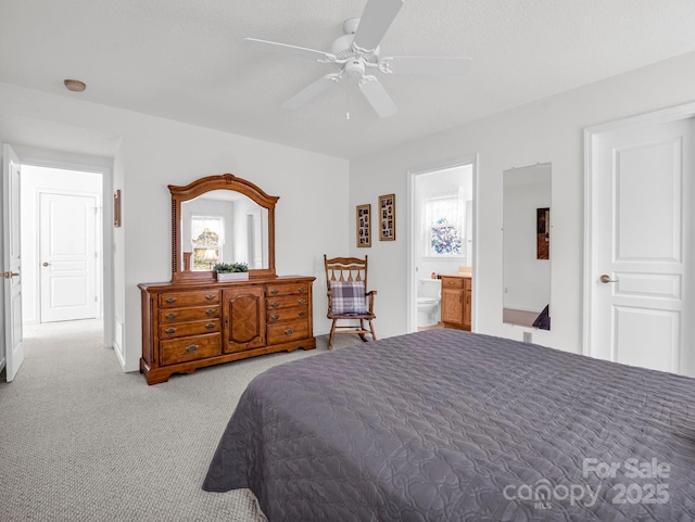 bedroom featuring ceiling fan, light colored carpet, a textured ceiling, and connected bathroom