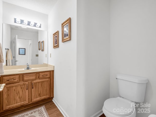 bathroom with hardwood / wood-style flooring, vanity, toilet, and a textured ceiling