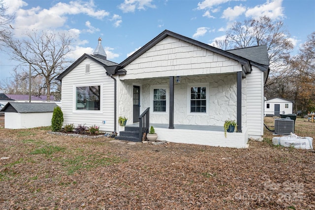 bungalow-style home featuring a porch and a storage shed