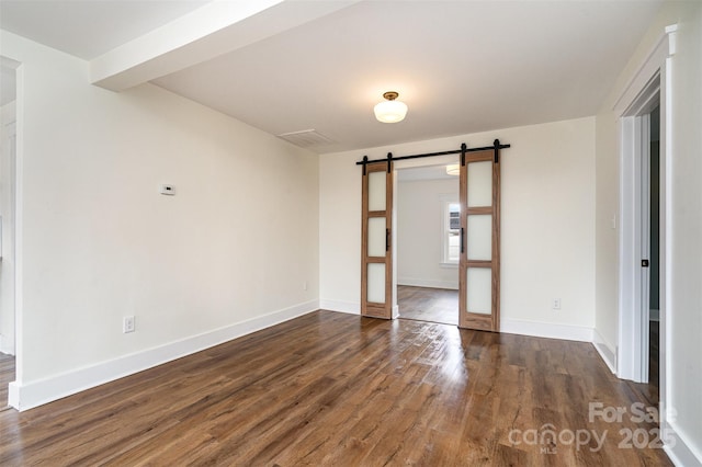 empty room with dark wood-type flooring and a barn door