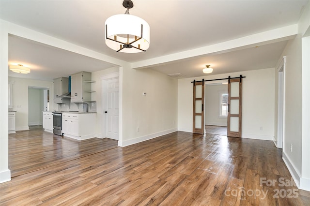 unfurnished living room with beamed ceiling, a barn door, and hardwood / wood-style floors