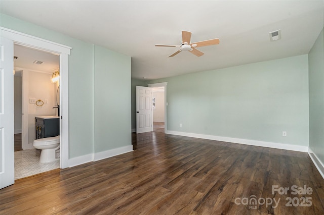 unfurnished bedroom featuring ensuite bath, dark hardwood / wood-style floors, and ceiling fan