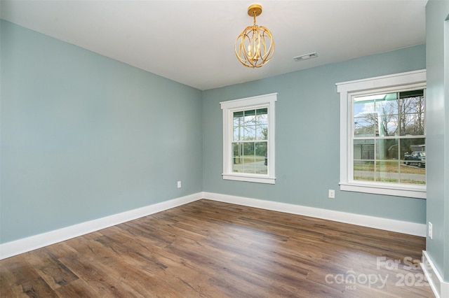 spare room with dark hardwood / wood-style flooring and a notable chandelier