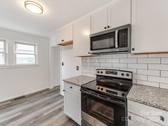 kitchen featuring decorative backsplash, appliances with stainless steel finishes, light stone countertops, crown molding, and white cabinets