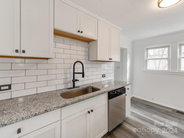 kitchen with light stone counters, stainless steel dishwasher, white cabinetry, and sink