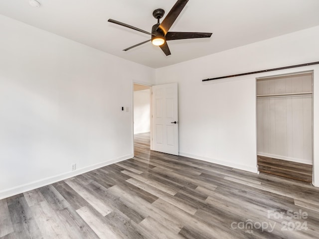 unfurnished bedroom with ceiling fan, wood-type flooring, and a closet