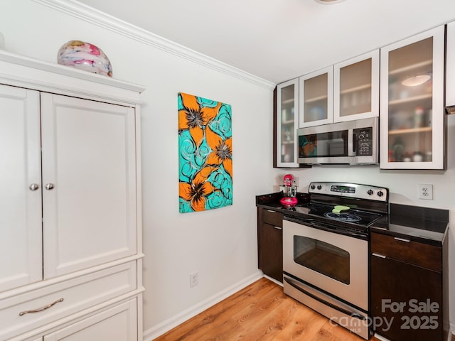 kitchen with white cabinets, appliances with stainless steel finishes, light hardwood / wood-style floors, and crown molding