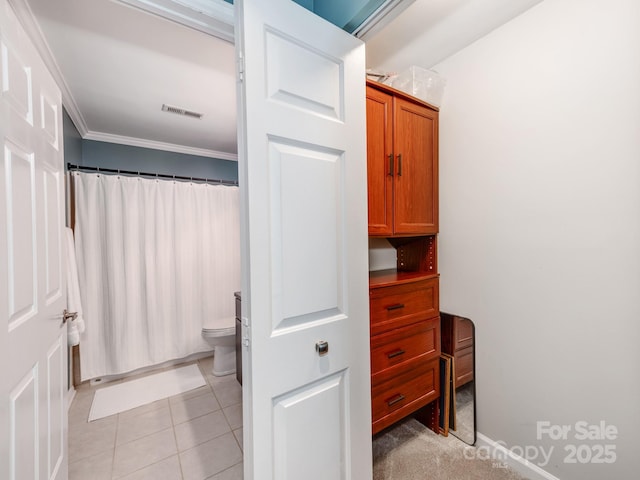 bathroom with toilet, tile patterned floors, and crown molding