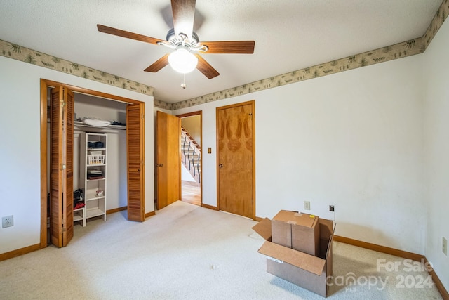 bedroom with ceiling fan, a closet, light colored carpet, and a textured ceiling