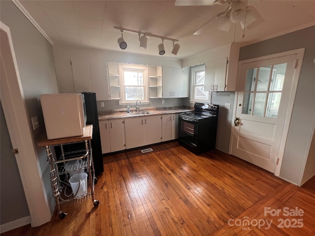 kitchen with black electric range oven, sink, dark wood-type flooring, ornamental molding, and white cabinets